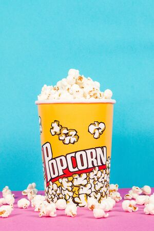 Yellow box of fresh popcorns on a pink and blue backgroundの写真素材