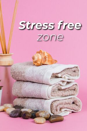 Spa essentials, candle, stones, towel and flowers on a pink backgroundの写真素材