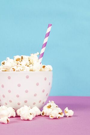 Fresh popcorn in a white pink bowl on pink and blue backgroundの写真素材