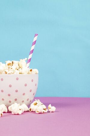 Fresh popcorn in a white pink bowl on pink and blue backgroundの写真素材