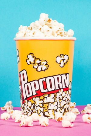 Yellow box of fresh popcorns on a pink and blue backgroundの写真素材