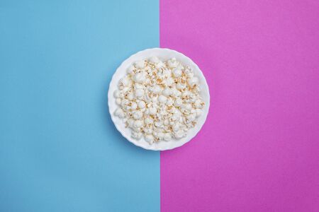 White bowl of popcorn on a blue and purple backgroundの写真素材