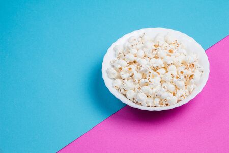 White bowl of popcorn on a blue and purple backgroundの写真素材