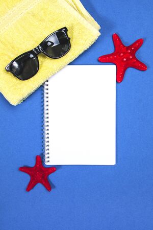 White blank page on a blue background with towel, sunglasses and starfishの写真素材