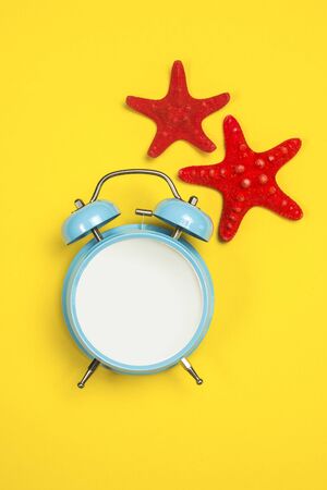 Blue alarm clock with starfishes on a yellow backgroundの写真素材
