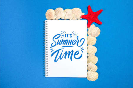 Starfish and seashells on a blue background with white page and text Summer Timeの写真素材
