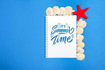 Starfish and seashells on a blue background with white page and text Summer Timeの写真素材