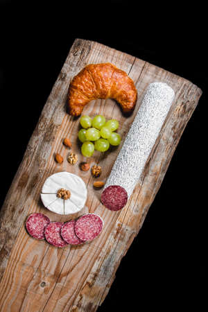 Dry meat and sausages with vegetables and cheese on a wooden tableの写真素材