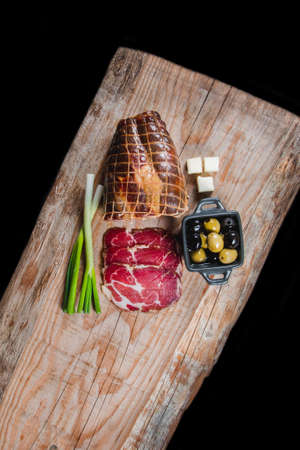 Dry meat and sausages with vegetables and cheese on a wooden tableの写真素材