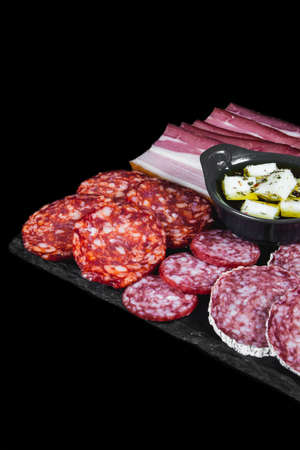 Dry variety of meat and sausages on a black plate and backgroundの写真素材