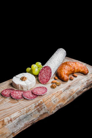 Dry meat sausage on a wooden plate with vegetablesの写真素材