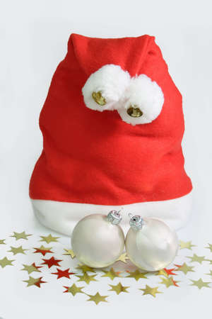 Santa hat with two white christmas tree balls and golden stars on whiteの写真素材