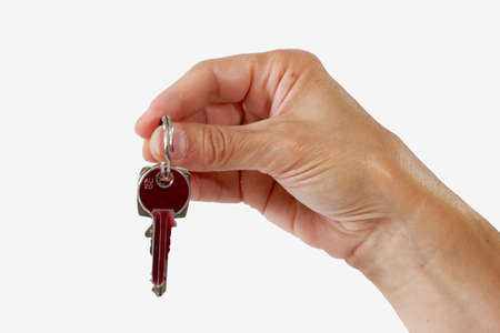Close up of a key in a female hand on light backgroundの写真素材