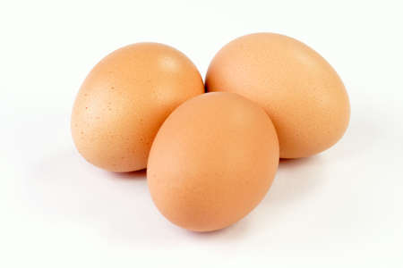 Close up of three brown eggs on bright background