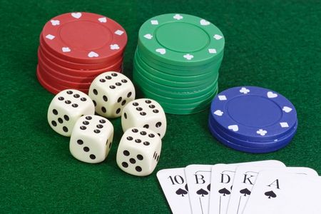Poker chips with playing cards on green background