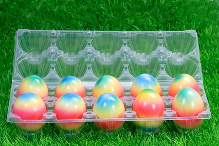 Paintes easter eggs in a plastic box on green backgroundの写真素材