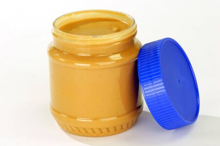 Glass of peanut butter on bright background