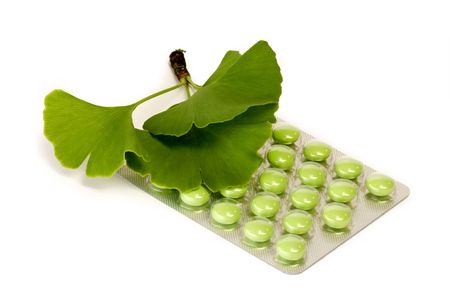 Green pills and ginkgo leaves - isolated on white background