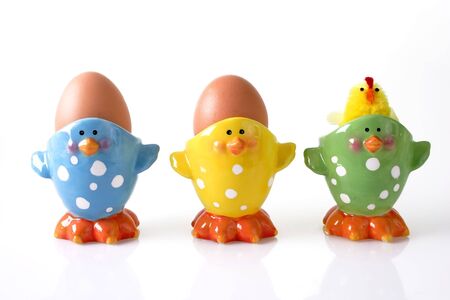 Eggs and chicken toy in eggcup on bright backgroundの写真素材