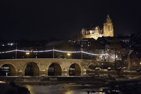 Ancient illuminated stone bridge with cathedral in backgroundの写真素材