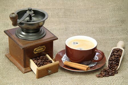 Delicious coffee with vintage coffee mill on brown backgroundの写真素材