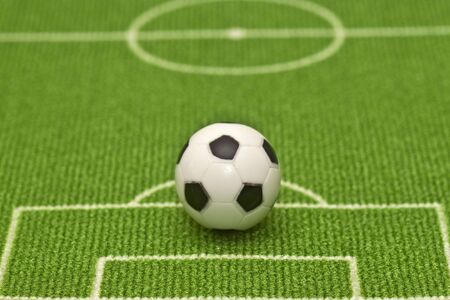 Symbol photo toy soccer ball on a football field. Shot in studio.