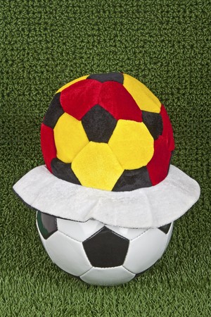 Soccer ball with fun cap on green grass background.の写真素材