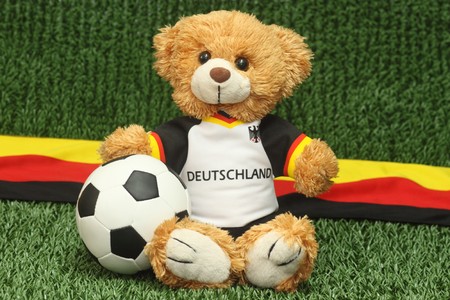 Teddy bear with football shirt on lawn backgroundの写真素材