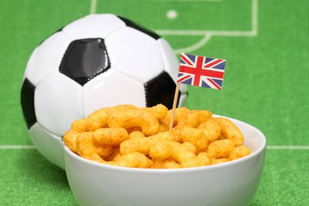 Soccer ball with crispy snacks in a bowl on green backgroundの写真素材