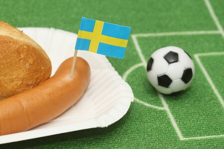 Sausage with roll on a football field background with soccer ballの写真素材