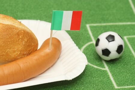 Sausage with roll on a football field background with soccer ballの写真素材