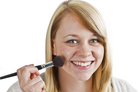 Attractive young woman applying blusher - isolated on whiteの写真素材