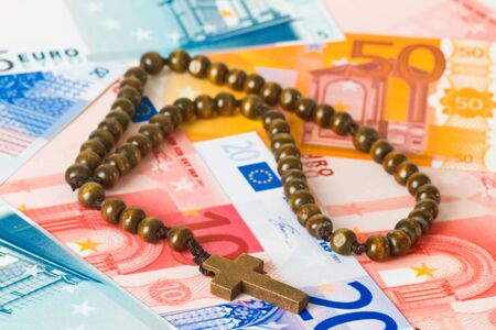 Wooden rosary on euro banknotesの写真素材