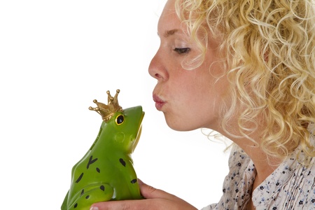 Young woman kissing a frog prince isolated on white backgroundの写真素材