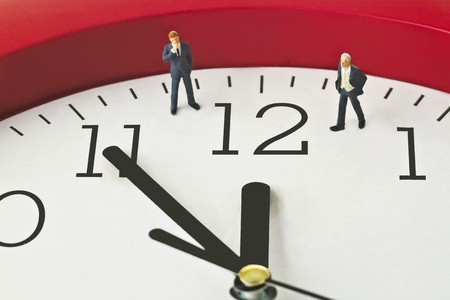 Figurine on clock face - concept - Five to twelve