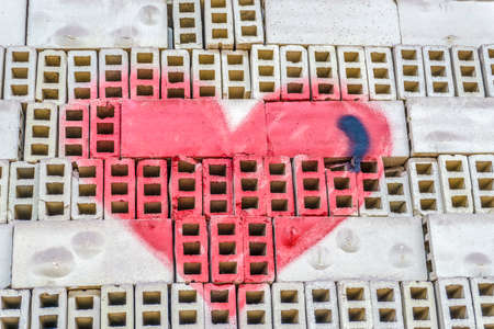 Red painted heart shape on a brick wall as background