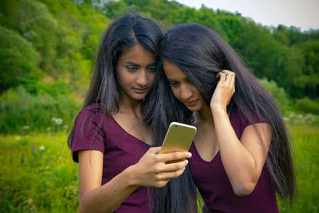 Beautiful young twins girls doing selfie: Outdoor Shot in Summer: Germany, Hessenの写真素材