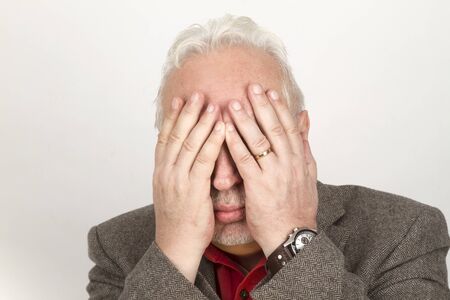 Senior hands on his face - on bright backgroundの写真素材