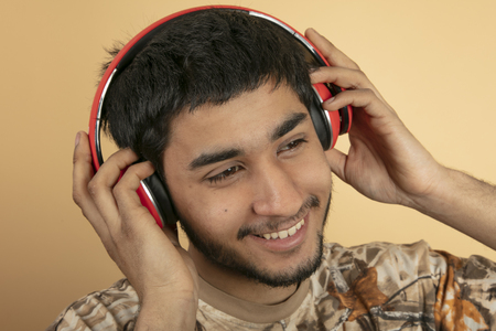 Young Man with Headphones listen to Music on beige Backgroundの写真素材