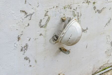 Old protection helmet hanging on weathered wallの写真素材