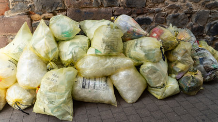 FRITZLAR 2019-07-10 in GERMANY Yellow trash bags on street on a stone wall