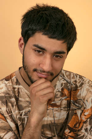 Friendly young Man with hand on his chin on beige Backgroundの写真素材