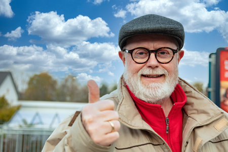 Outdoor Portrait from an optimistic Senior in winter cloth shows thumb upの写真素材
