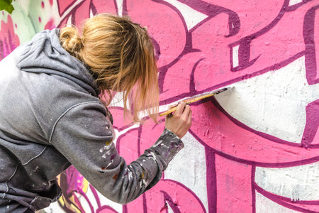 WETZLAR, GERMANY - 23.05.2021: Young female artist doing artificial typography colorful graffiti senic on house facade in WETZLAR; GERMANYのeditorial素材