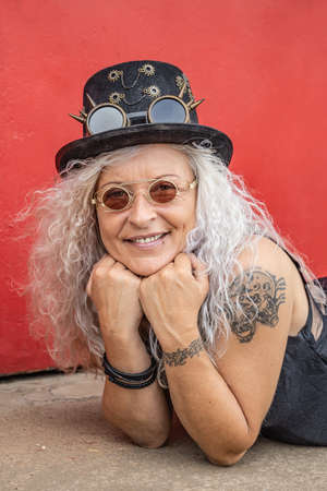 Beautiful Steampunk Lady keeps her chin up with her hands with red background.の写真素材