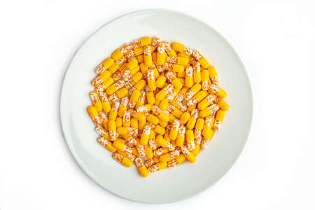 Yellow capsules on a white plate isolated on white backgroundの写真素材