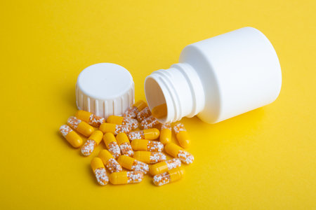 Yellow Pills with a white pill box on yellow backgroundの写真素材
