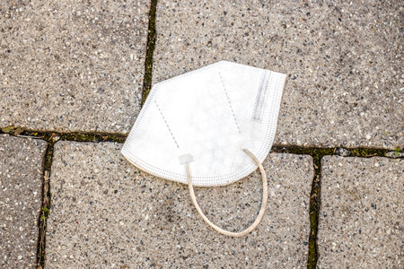 Medical mask on the sidewalk. Throwing a used face mask away on the street is wrong.の写真素材