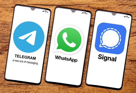 HUETTENBERG, GERMANY 2021-12_14: TELEGRAM WHATSAPP and SIGNAL App on a cellphone screen. Top view on wooden background.のeditorial素材
