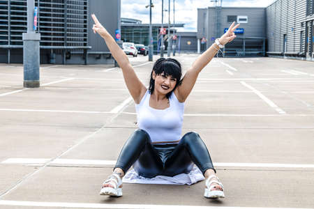 Young woman sitting on the floor and stretching out armsの写真素材